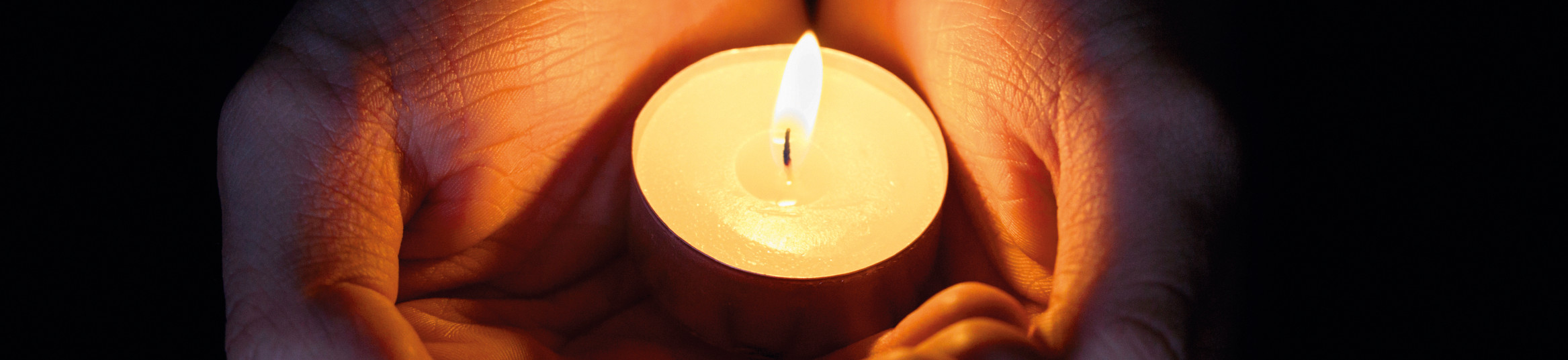 female teen hands holding burning candle in the dark